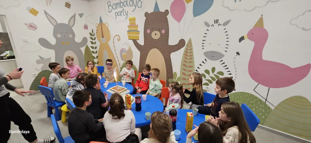 Djeca sjede za stolom i slave rođendan tortom